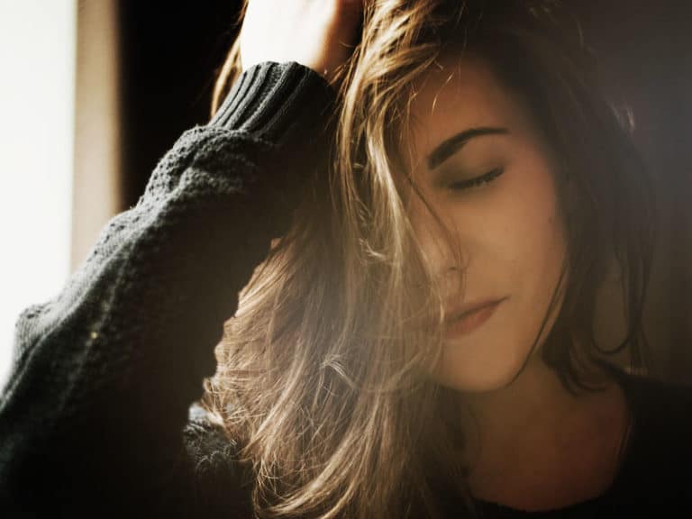 Woman thinking with hand on her hair to illustrate the topic of hair loss